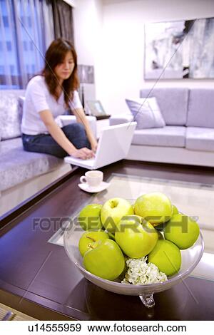 Stock Photo - Young woman using laptop in living room. Fotosearch