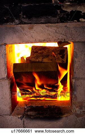 Stock Image - Close up of logs in ceramic kiln's entrance firing. Fotosearch