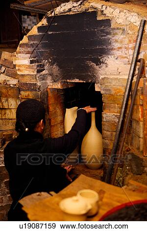 Stock Photo - Potter by ceramic kiln's exit, rear view. Fotosearch