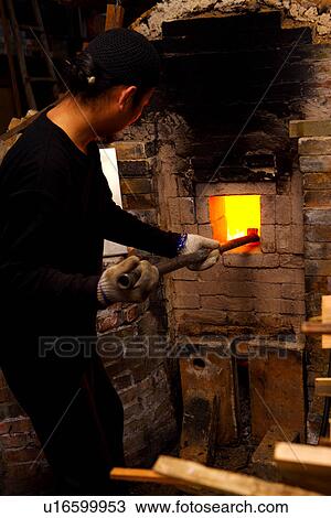 Stock Image - Potter clearing charcoal, side view. Fotosearch