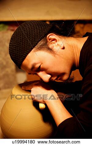 Stock Image - Potter listening pottery's sound, side view. Fotosearch
