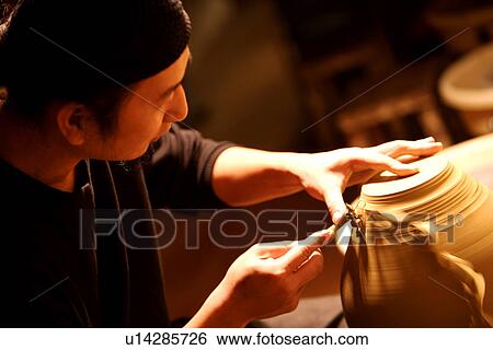 Stock Photograph - Potter making a vase, carving. Fotosearch