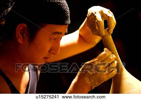Stock Image - Potter molding clay body, side view. Fotosearch