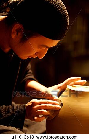 Stock Image - Potter molding clay, side view. Fotosearch