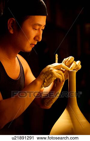Stock Image - Potter refining its shape, side view. Fotosearch