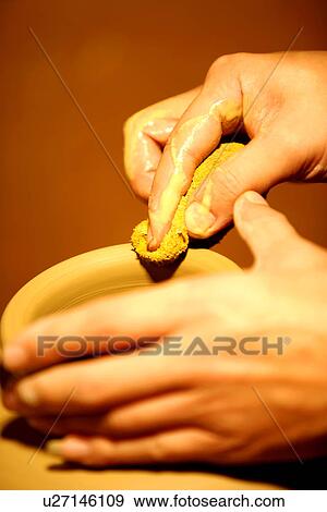 Stock Photo - Potter refining mouth of pottery by using towel, focus on hands. Fotosearch