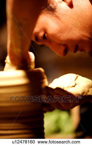Stock Image - Potter refining mouth of pottery, side view. Fotosearch