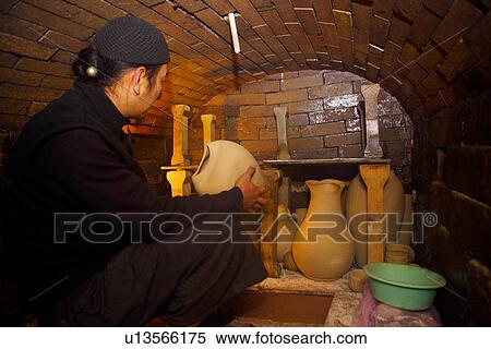 Stock Photography - Potter sitting in ceramic kiln, side view. Fotosearch