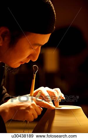 Stock Photo - Potter trimming clay body, side view. Fotosearch