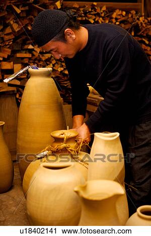 Stock Image - Potter using straws for ceramics, side view. Fotosearch