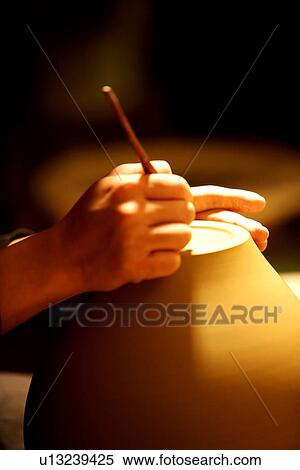 Stock Photography - Potter writing bottom stamp of ceramic ware, close up of hands. Fotosearch