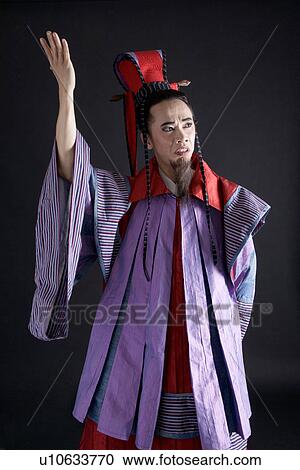 Stock Image - A man with hand raised wearing traditional clothing. Fotosearch