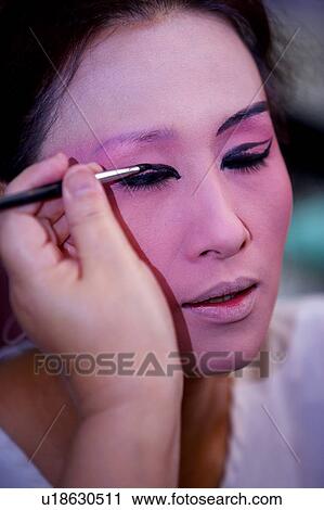 Stock Image - Makeup artists applying makeup to performer's eyes. Fotosearch