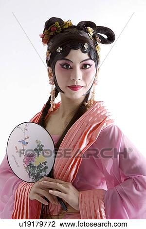 Stock Image - Mature woman wearing traditional clothing holding fan. Fotosearch