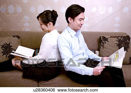 Stock Photograph - Couple back to back reading on sofa. Fotosearch
