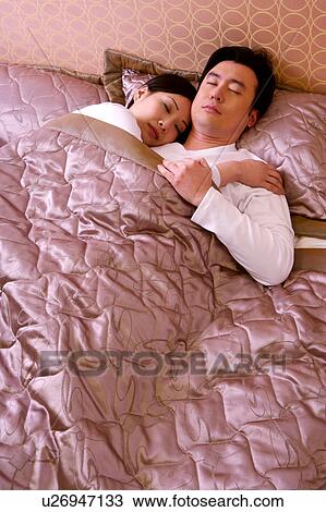 Stock Image - Couple embracing sleeping on bed. Fotosearch