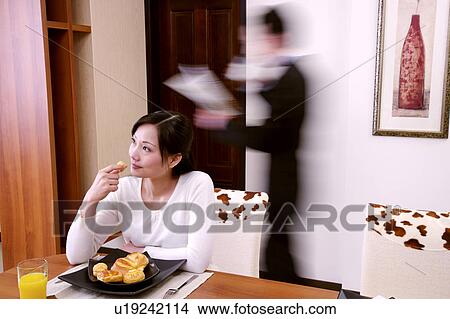 Couple in home, wife eating breakfast, man reading newspaper (blurred motion) View Large Photo Image Picture - Couple in home, wife eating breakfast, man reading newspaper (blurred motion). Fotosearch