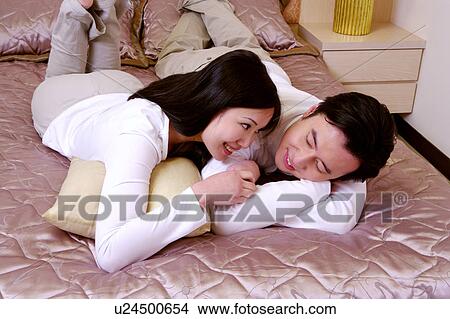 Couple lying on bed View Large Photo Image Picture - Couple lying on bed. Fotosearch