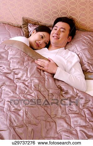 Stock Photograph - Couple lying on bed. Fotosearch