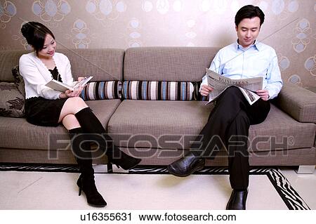 Couple on sofa, man reading newspaper, woman reading book View Large Photo Image Stock Image - Couple on sofa, man reading newspaper, woman reading book. Fotosearch