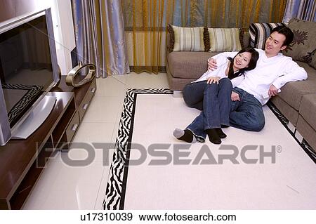 Couple sitting on floor leaning on sofa View Large Photo Image Stock Photo - Couple sitting on floor leaning on sofa. Fotosearch