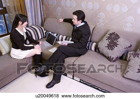 Couple sitting on sofa in living room View Large Photo Image Stock Photo - Couple sitting on sofa in living room. Fotosearch
