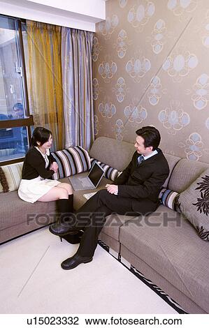 Stock Image - Couple sitting on sofa talking. Fotosearch