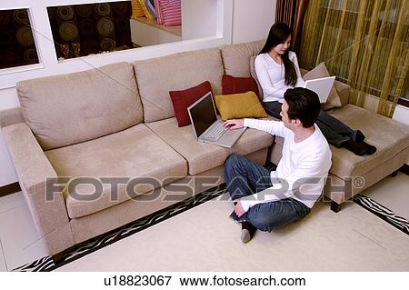 Stock Photo - Couple using laptop in living room. Fotosearch