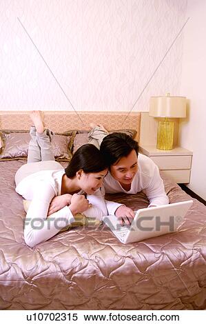 Stock Photography - Couple using laptop on bed. Fotosearch