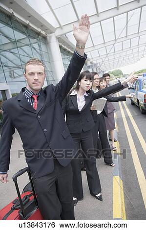 Business executives hailing a taxi at an airport View Large Photo Image Stock Photograph - Business executives hailing a taxi at an airport. Fotosearch
