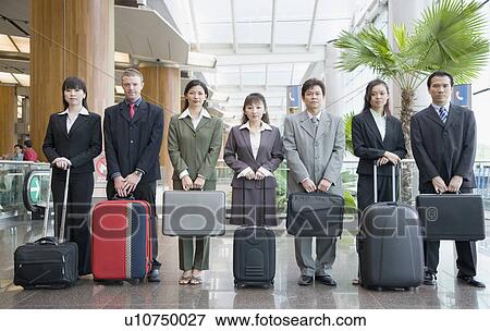 Stock Photo - Business executives standing at an airport lounge with their luggage. Fotosearch