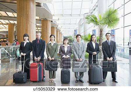 Stock Photo - Business executives standing at an airport lounge with their luggage. Fotosearch