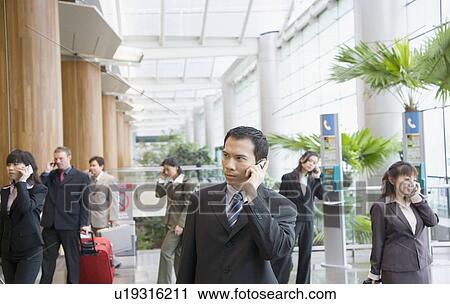 Business executives talking on mobile phones and leaving an airport lounge View Large Photo Image Stock Image - Business executives talking on mobile phones and leaving an airport lounge. Fotosearch