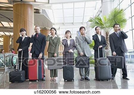 Business executives talking on mobile phones at an airport lounge View Large Photo Image Stock Photograph - Business executives talking on mobile phones at an airport lounge. Fotosearch