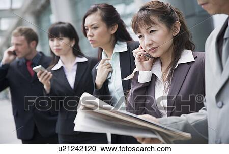 Stock Image - Business executives waiting for taxi at an airport. Fotosearch