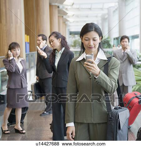 Businesswoman looking at a mobile phone at an airport View Large Photo Image Stock Photo - Businesswoman looking at a mobile phone at an airport. Fotosearch