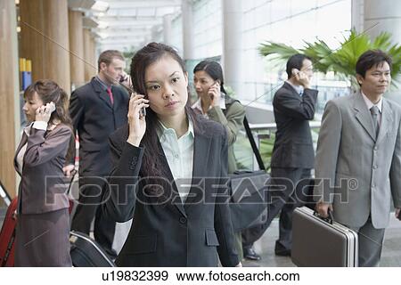 Businesswoman talking on a mobile phone and leaving an airport View Large Photo Image Stock Photo - Businesswoman talking on a mobile phone and leaving an airport. Fotosearch