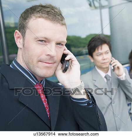 Close-up of two businessmen talking on mobile phones View Large Photo Image Picture - Close-up of two businessmen talking on mobile phones. Fotosearch