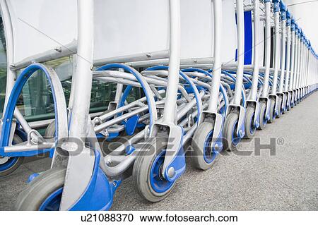 Stock Image - Luggage carts in a row outside an airport. Fotosearch