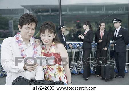 Mature couple looking at an airplane ticket with pilots and cabin crews standing in the background View Large Photo Image Stock Photograph - Mature couple looking at an airplane ticket with pilots and cabin crews standing in the background. Fotosearch