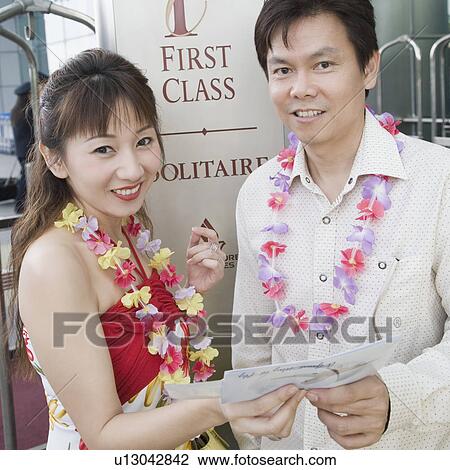 Stock Image - Portrait of a mature couple standing and holding an airplane ticket. Fotosearch