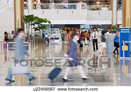 Stock Photo - Side profile of a businessman and a businesswoman leaving an airport. Fotosearch
