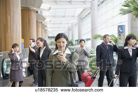 Businesswoman looking at a mobile phone and standing at an airport View Large Photo Image Stock Photography - Businesswoman looking at a mobile phone and standing at an airport. Fotosearch