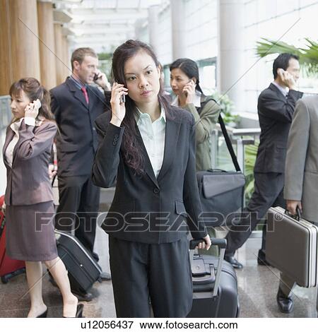 Businesswoman talking on a mobile phone and leaving an airport View Large Photo Image Stock Photo - Businesswoman talking on a mobile phone and leaving an airport. Fotosearch