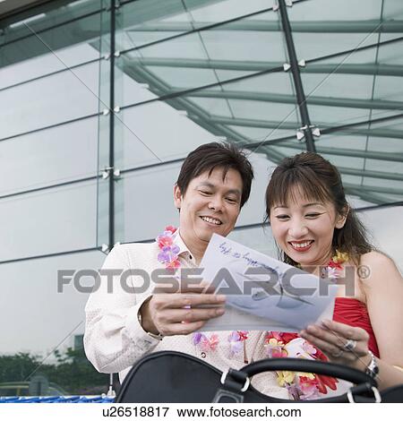 Close-up of a mature couple holding an airplane ticket and smiling View Large Photo Image Stock Photo - Close-up of a mature couple holding an airplane ticket and smiling. Fotosearch