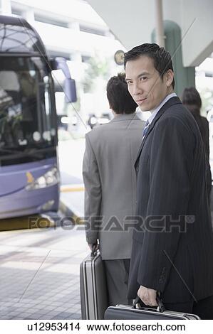 Picture - Portrait of a businessman holding a suitcase and walking. Fotosearch