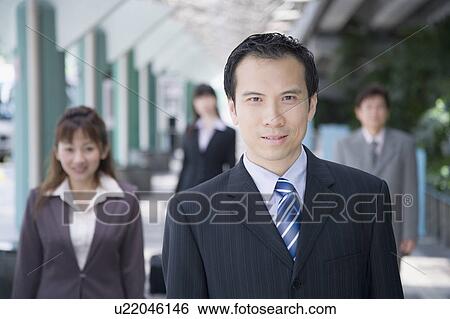 Stock Photograph - Portrait of a businessman smiling with three business executives in the background. Fotosearch