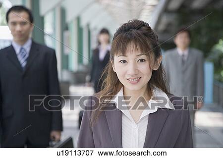 Portrait of a businesswoman smiling with three business executives in the background View Large Photo Image Stock Photo - Portrait of a businesswoman smiling with three business executives in the background. Fotosearch