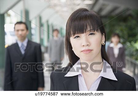 Stock Photo - Portrait of a businesswoman with three business executives in the background. Fotosearch