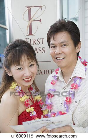Stock Photography - Portrait of a mature couple standing and holding an airplane ticket. Fotosearch